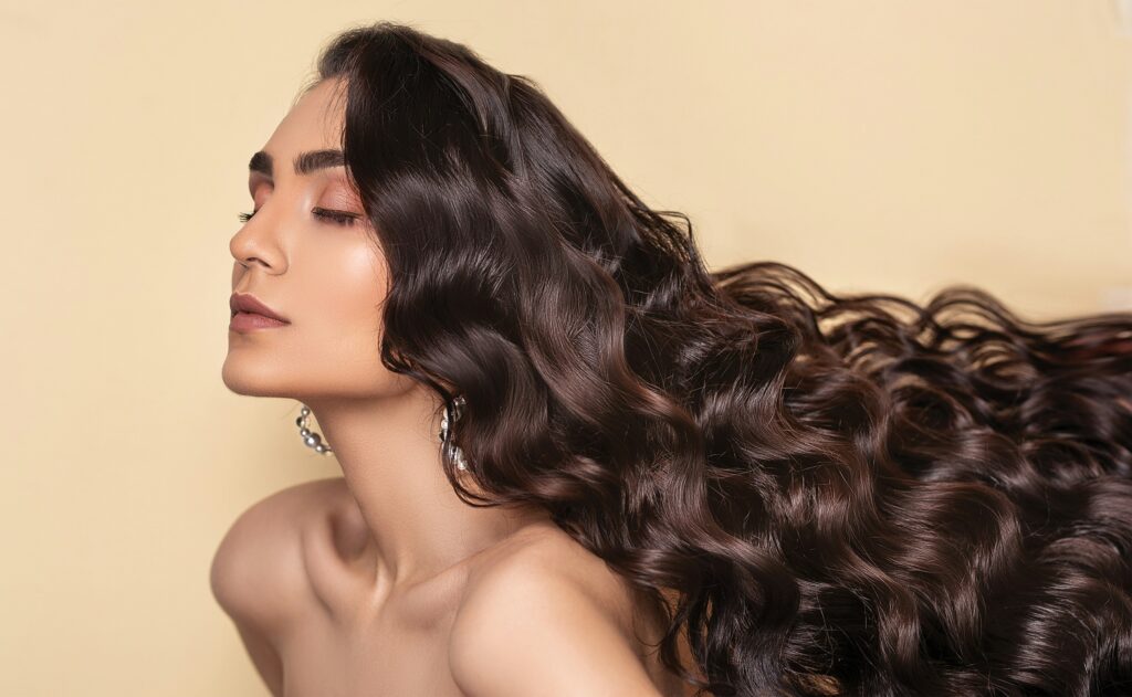 Woman with long, healthy, glossy wavy hair displaying natural shine and volume.